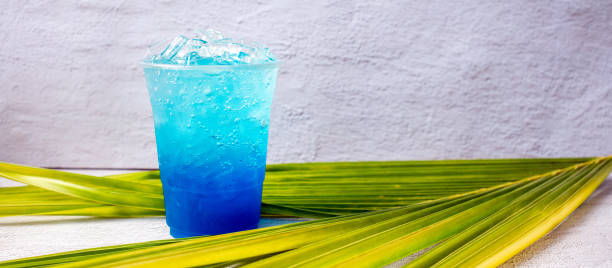 Blue Hawaiian drink in a plastic glass and coconut leaves.