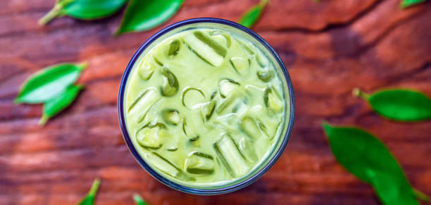 iced matcha latte, green tea with milk in a glass with ice on wooden