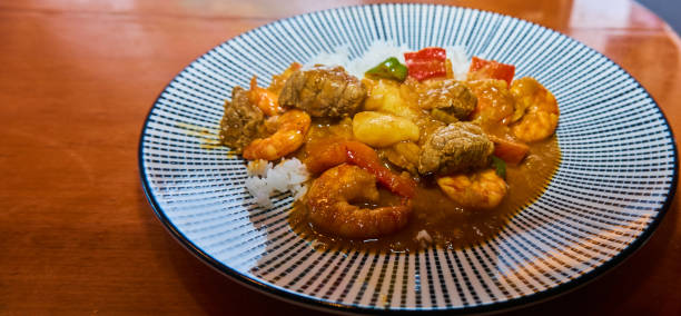East Asian curry rice with pork, vegetables and shrimps in a hot brown sauce