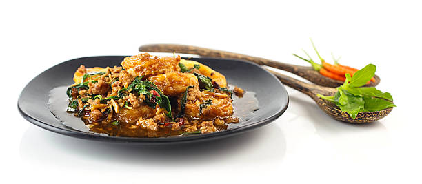 Dish of stir fried eggs tofu with pork and holy basil on white