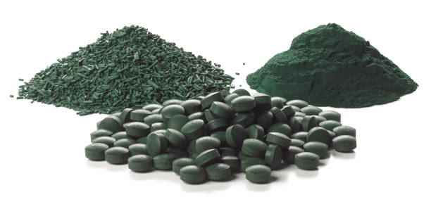 Close up of organic spirulina tablets, flakes and powder over white background.