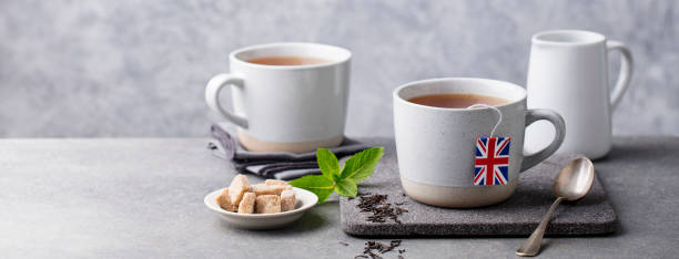 Tea in mugs with British flag tea bag label. Grey background. Copy space